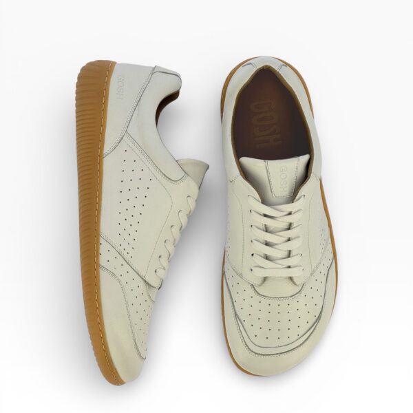 Side-top view of a barefoot white suede shoe