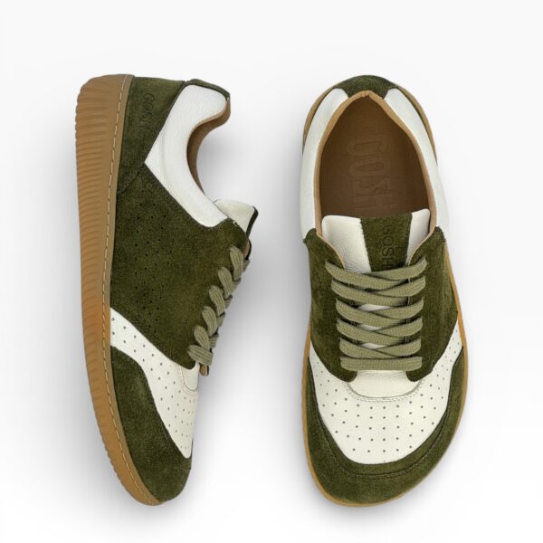 Side-top view of a barefoot green-white suede shoe