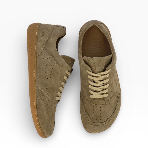 Side-top view of a barefoot beige suede shoe